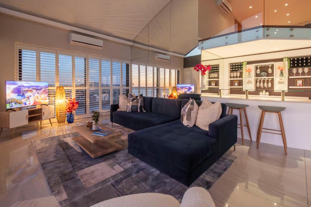 Una sala de estar con un sofá y un bar. en Penthouse with a view to die for!, en Ciudad del Cabo