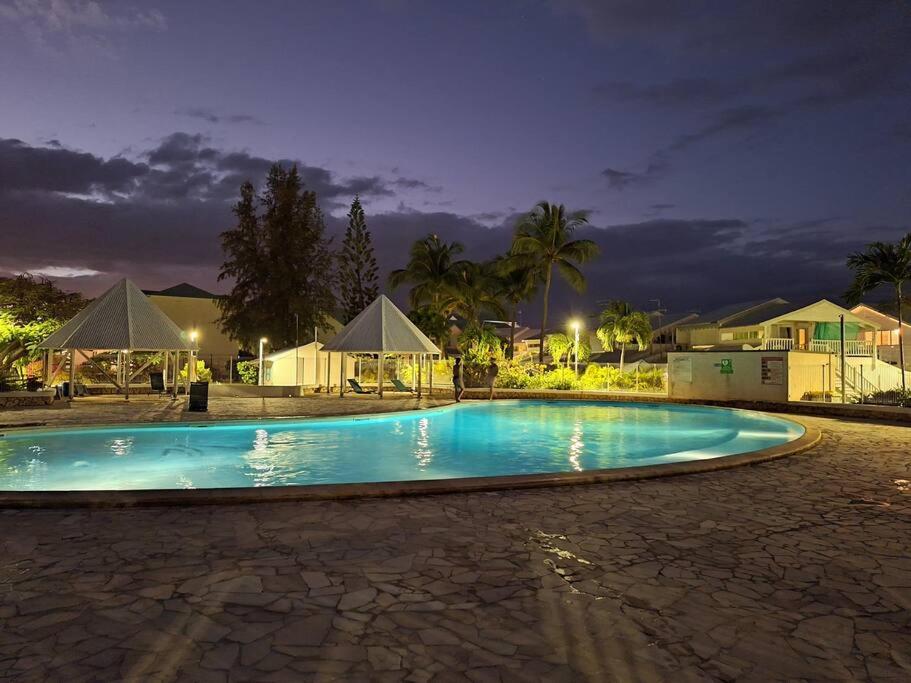 an empty swimming pool at night with houses and trees at Chez Marine ô Marines in Saint-François