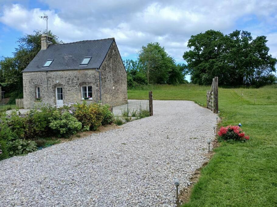 une ancienne maison en pierre sur une route en gravier dans l'établissement Gîte Les Pages, à Yvetot Bocage