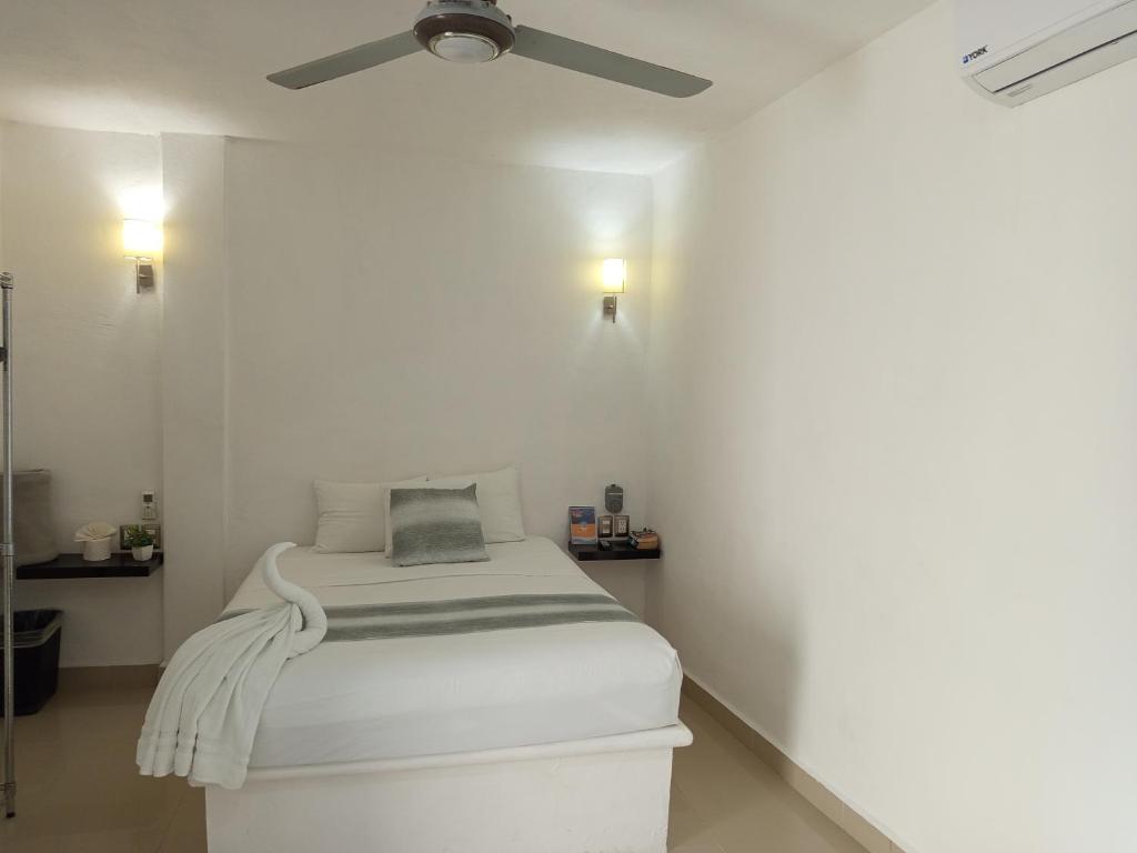 a white room with a bed with a ceiling fan at Mi habitat holbox-Maravilla natural in Holbox Island