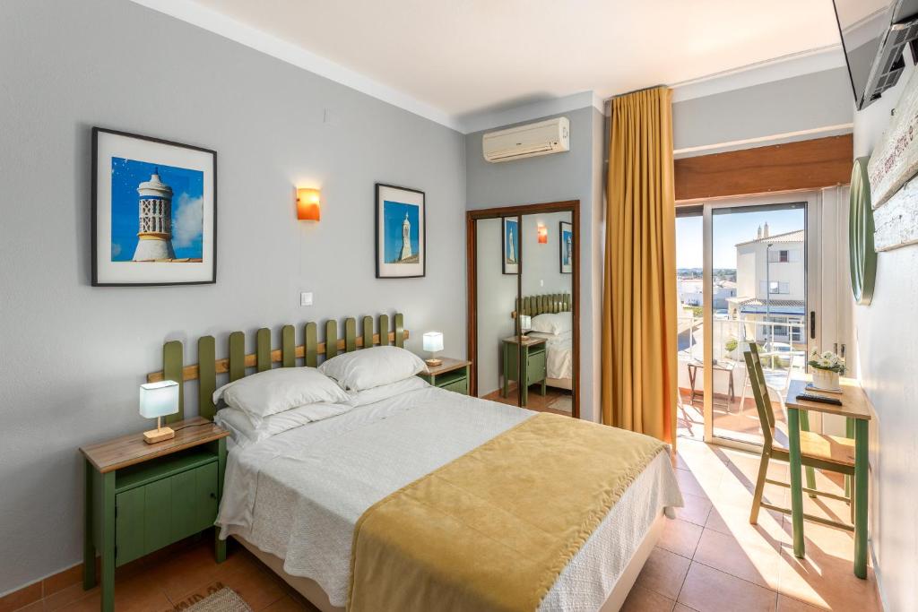 a bedroom with a bed and a balcony at Guest House Oliveira in Boliqueime