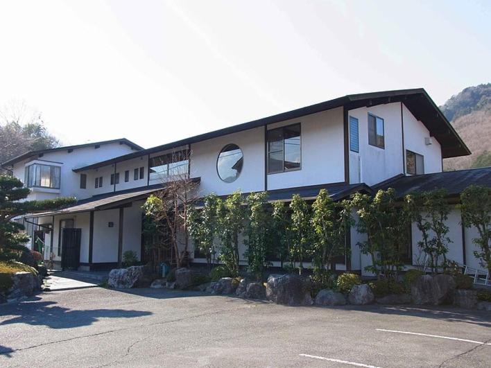 un gran edificio blanco con árboles delante de él en Pension Amagiji, en Izu