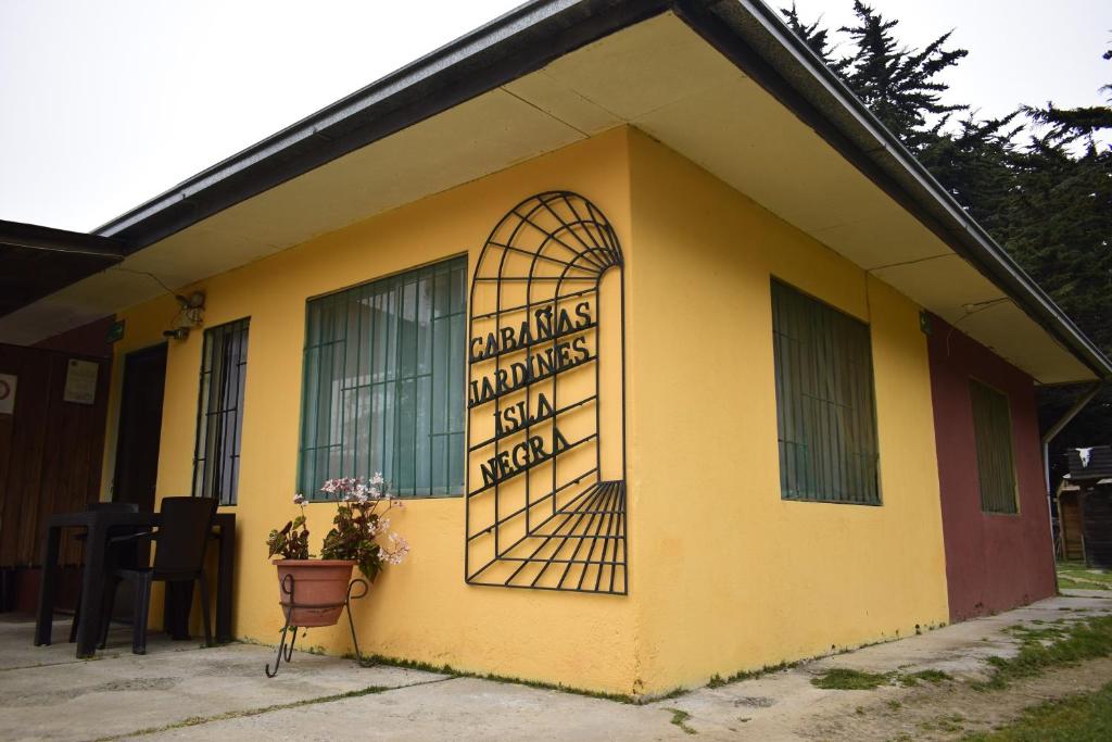 a yellow building with a sign on the side of it at Cabañas Jardines de Isla Negra in El Quisco