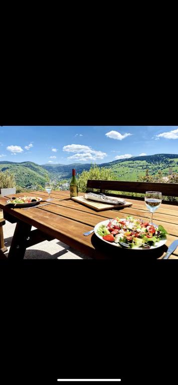- une table avec une assiette de nourriture et un verre de vin dans l'établissement Chalet Solie, à La Bresse