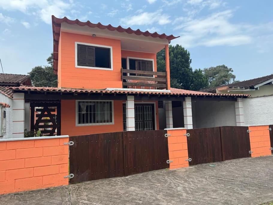 a orange house with a fence in front of it at Casa Praia Riviera São Lourenço in Bertioga