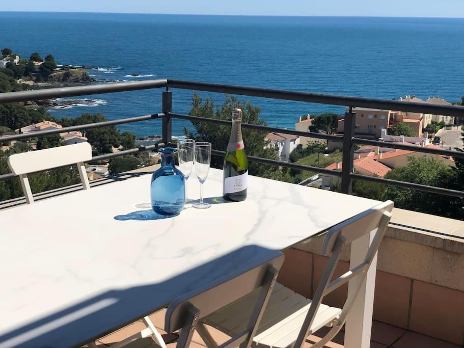 a table with two bottles and glasses on a balcony at Sensational Apartment with panoramic views in Llança
