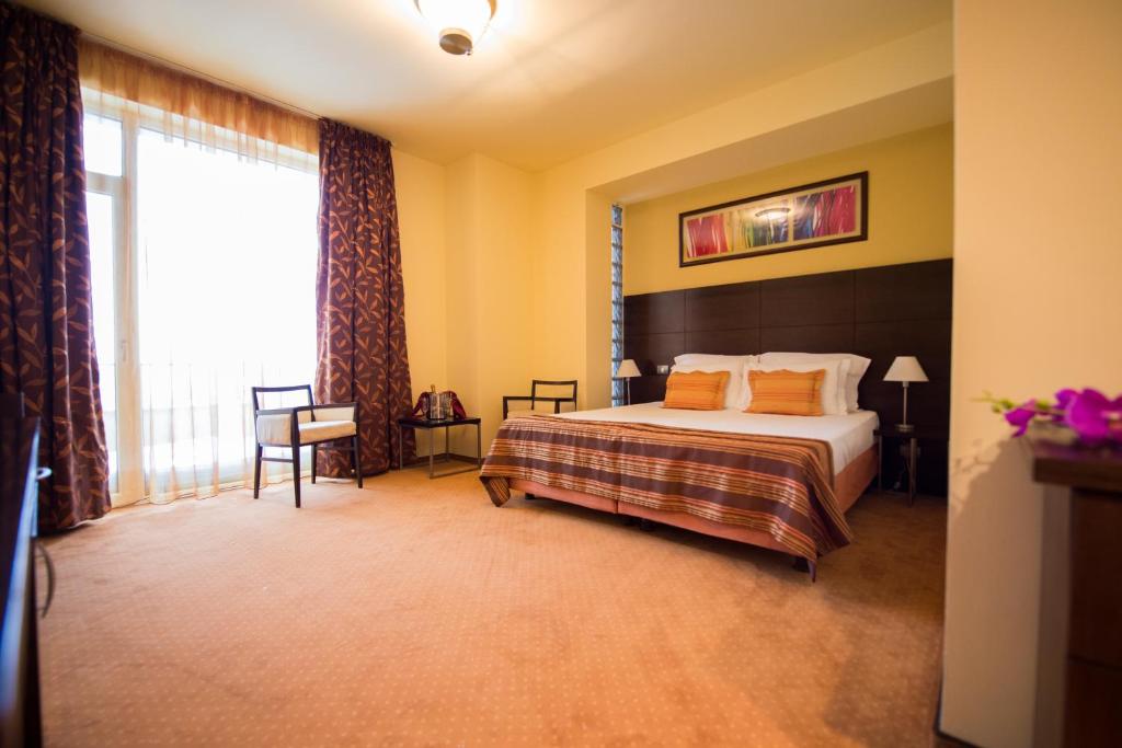 ママイアにあるImago Boutique Hotelのベッドと大きな窓が備わるホテルルームです。