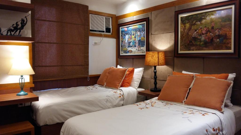 ein Hotelzimmer mit 2 Betten und Gemälden an der Wand in der Unterkunft Stay Amare Blue Ateneo in Manila