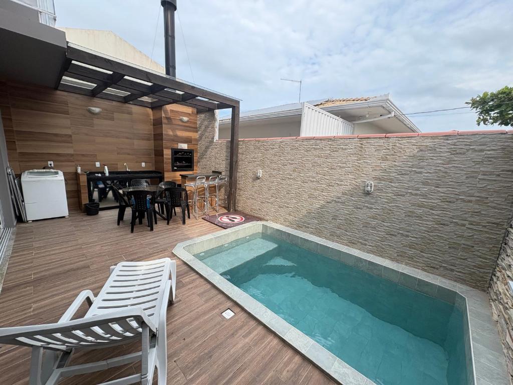 a swimming pool on a patio with a table and chairs at Linda casa 3 Praia Ponta do Papagaio 190mt mar in Palhoça