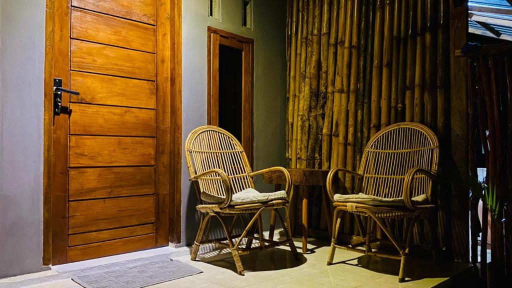 two chairs sitting in a room with a door at Sentigi Homestay Gili Gede in Gili Gede