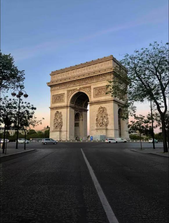 une arche avec des voitures garées devant une rue dans l'établissement 2 bedroom appartement champs Élysée, à Paris
