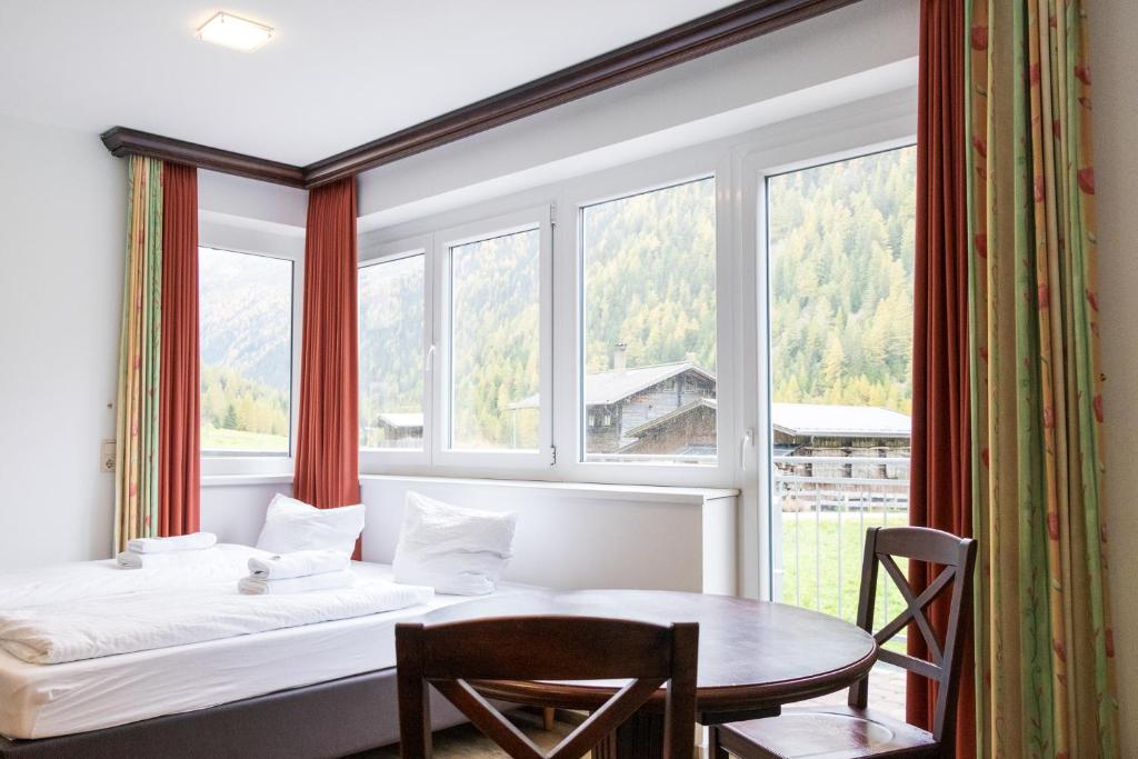 a bedroom with a bed and a table in front of a window at International House Sölden Studio mit Bergblick ZW 1 in Sölden
