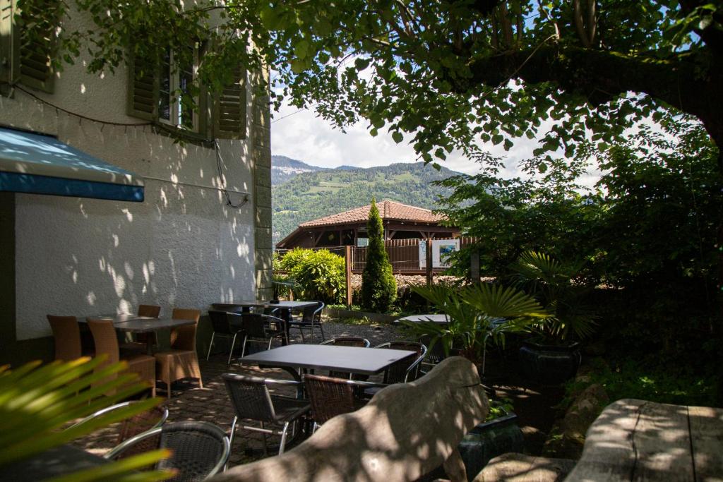 eine Terrasse mit Tischen und Stühlen und ein Gebäude in der Unterkunft Au Bord Du Lac in Därligen