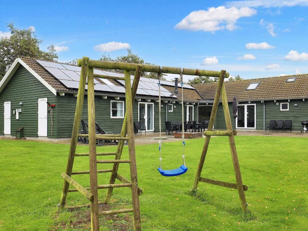 a wooden swing set in a yard with a house at 5 star holiday home in Idestrup in Marielyst