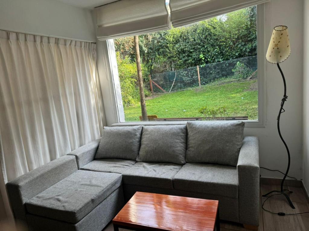 un soggiorno con un divano e una finestra di Duplex Mardifiore Pinamar a Pinamar