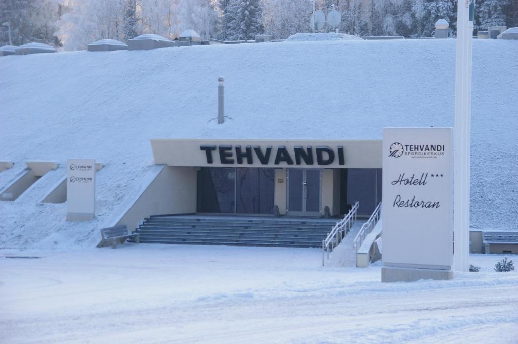 a building with a sign in the snow at Tehvandi Hotell in Otepää