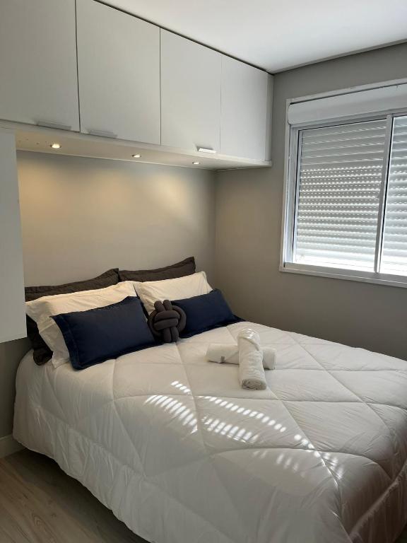 a large white bed in a bedroom with a window at Apartamento Central 2 Quartos c Garagem in Pelotas