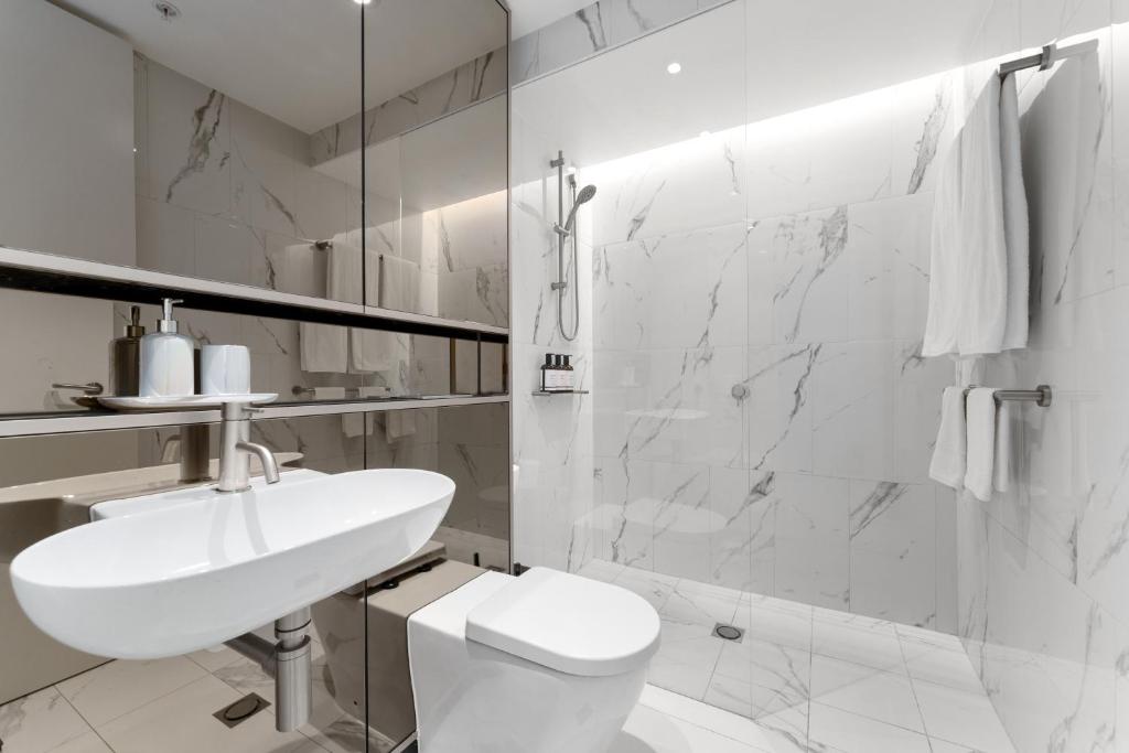 a white bathroom with a sink and a toilet at Harbour Views, Fireworks & Secure Parking in Sydney
