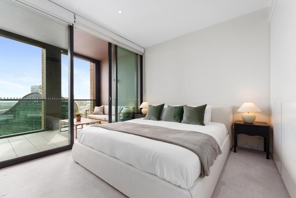 a white bedroom with a large bed and a balcony at Harbour Views, Fireworks & Secure Parking in Sydney