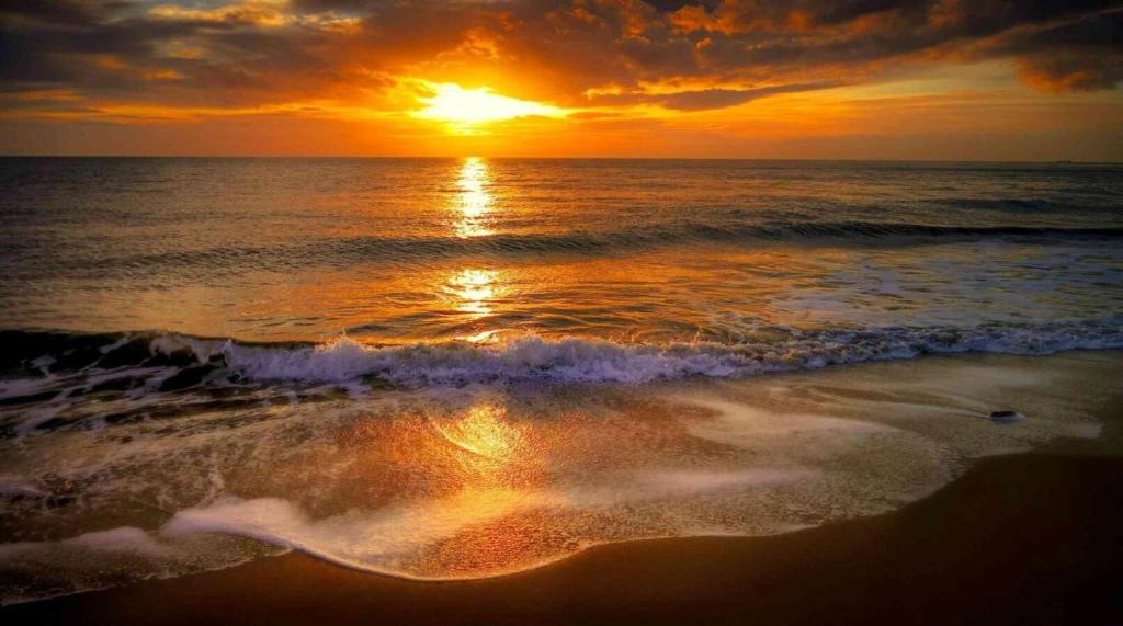 a sunset on the beach with the ocean at Cat Ba Madame Duyen Hotel in Cat Ba