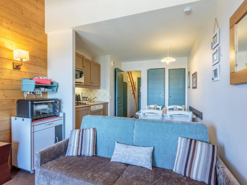 un salon avec un canapé bleu et une cuisine dans l'établissement Charmant duplex 2 pièces, 4 pers., balcon, casier à skis - La Plagne - FR-1-353-146, à La Plagne Tarentaise