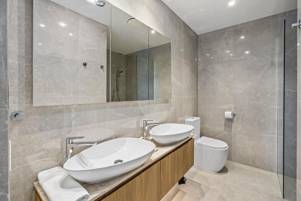 a bathroom with a sink and a toilet and a mirror at Waterfront 2-Bed Oasis - Pool Steam Jacuzzi Gym in Kawana Waters