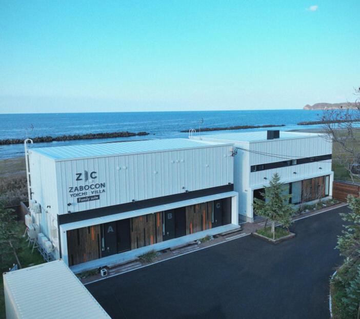 a large white building with the ocean in the background at ZABOCON Yoichi Villa in Yoichi