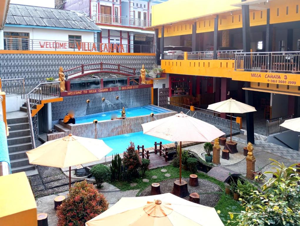 an overhead view of a swimming pool with umbrellas at Villa Cahaya 3 Guci Mitra RedDoorz in Tuwel