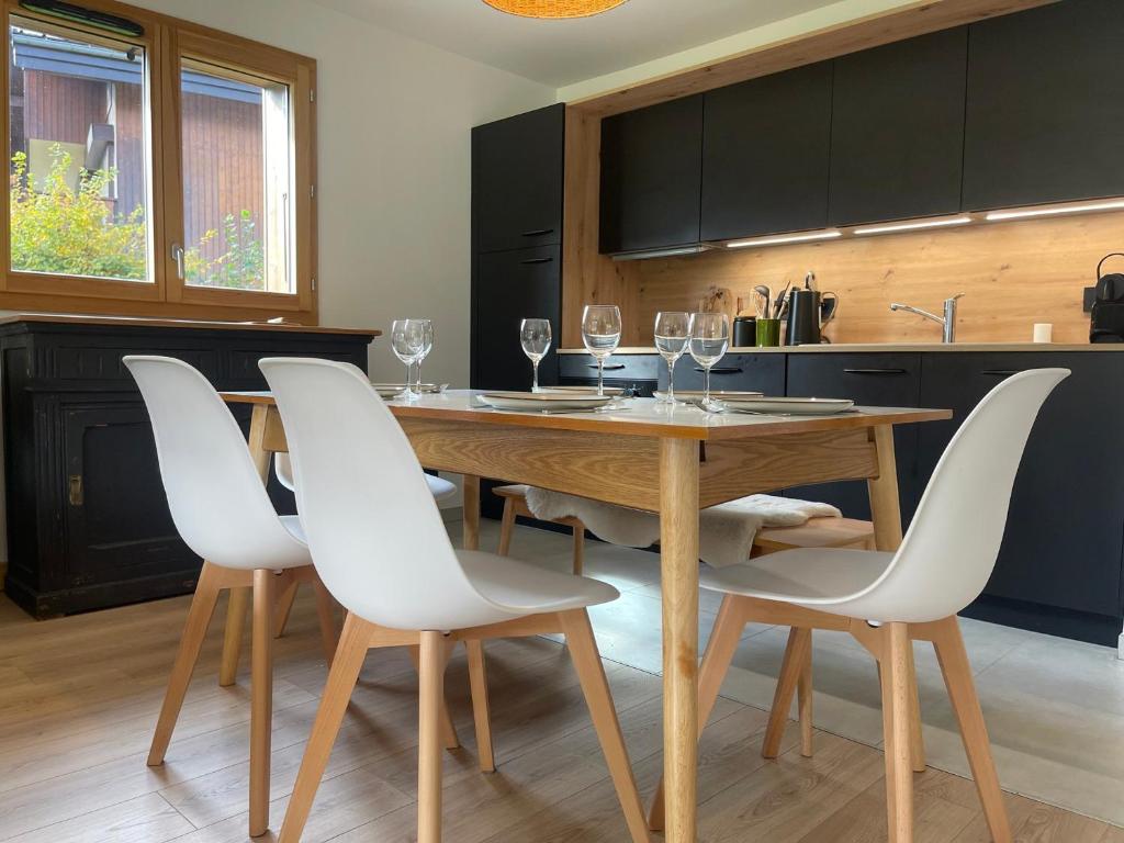 - une cuisine avec une table en bois et des chaises blanches dans l'établissement Appartement moderne T4 avec jardin dans résidence neuve - FR-1-624-167, à Samoëns
