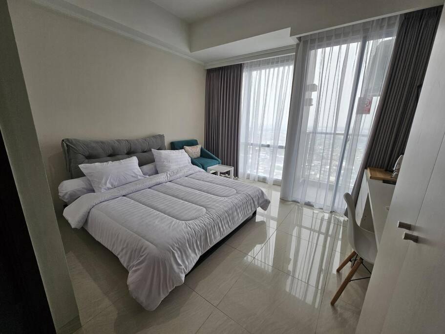a bedroom with a large bed with white sheets at Green Sedayu Apartment Deluxe by Ellison in Jakarta
