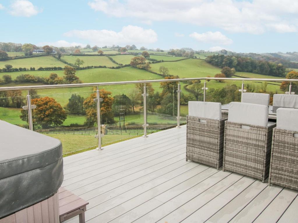 a deck with chairs and a view of the countryside at Bwncath in Welshpool