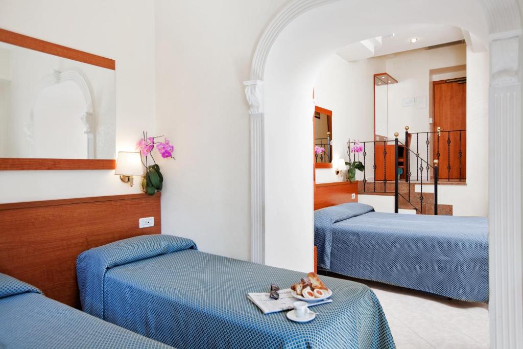 a room with three beds with blue sheets at Hotel Delle Muse in Rome