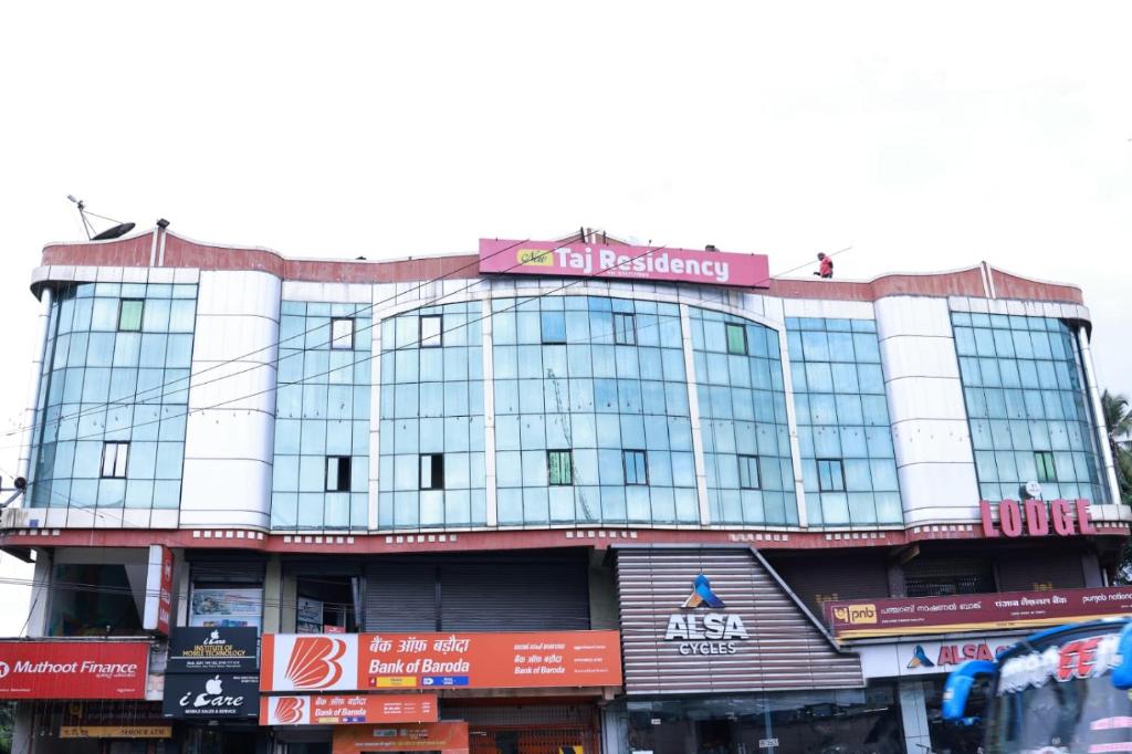 a large building with a sign on top of it at TAJ Residency in Mannārakkāt