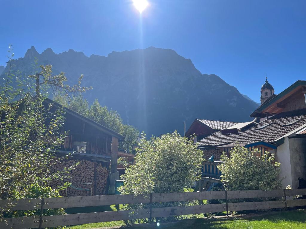 a house with a fence and a mountain in the background at Ferienwohnung mit Terrasse und Garten mit Blick auf das Karwendelgebirge in Mittenwald