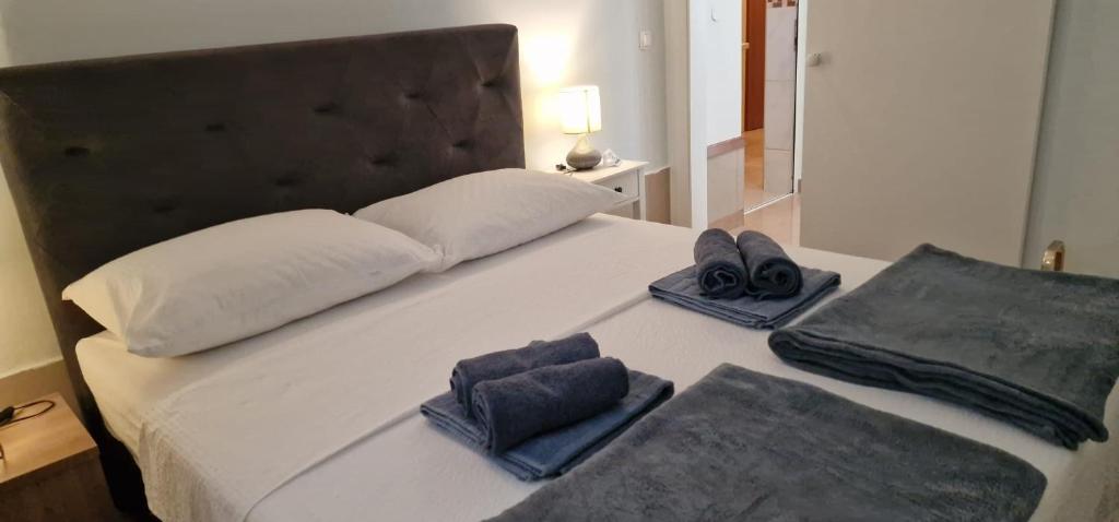 a bed with two pillows and towels on it at Carla Apartment Opuzen Modern Oasis and Comfort in Opuzen