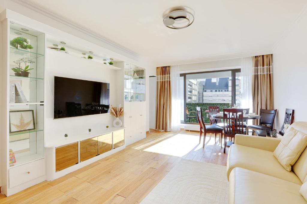 un salon avec un canapé, une télévision et une table dans l'établissement À 1 minute du métro et Parking privé, à Paris