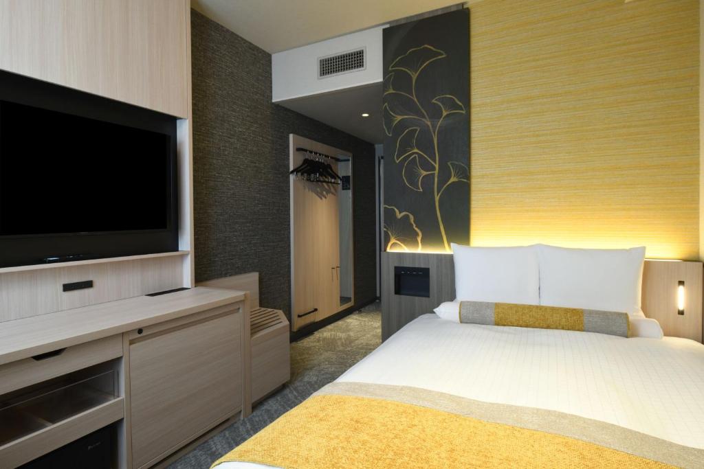 a bedroom with a bed and a flat screen tv at HOTEL MYSTAYS Ochanomizu Conference Center in Tokyo