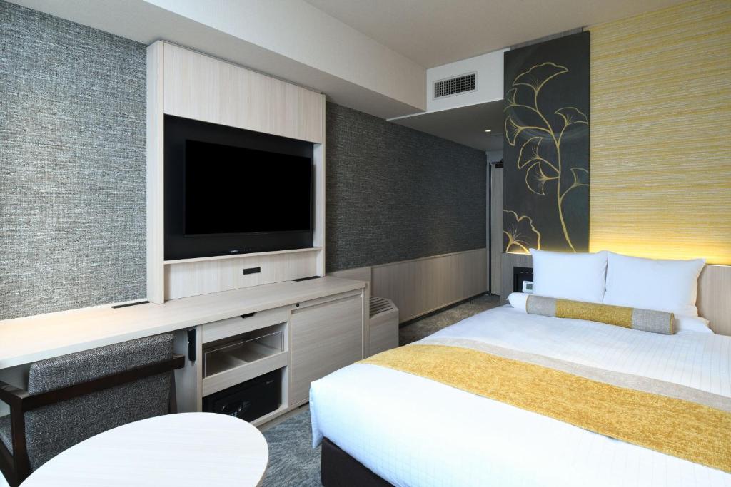 a hotel room with a bed and a flat screen tv at HOTEL MYSTAYS Ochanomizu Conference Center in Tokyo