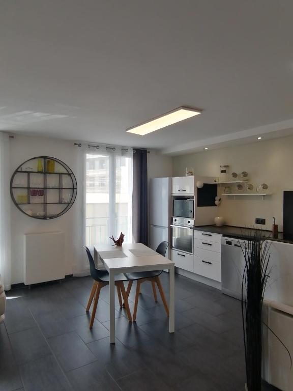 - une cuisine avec une table et des chaises blanches dans la chambre dans l'établissement Bel hébergement, au Havre