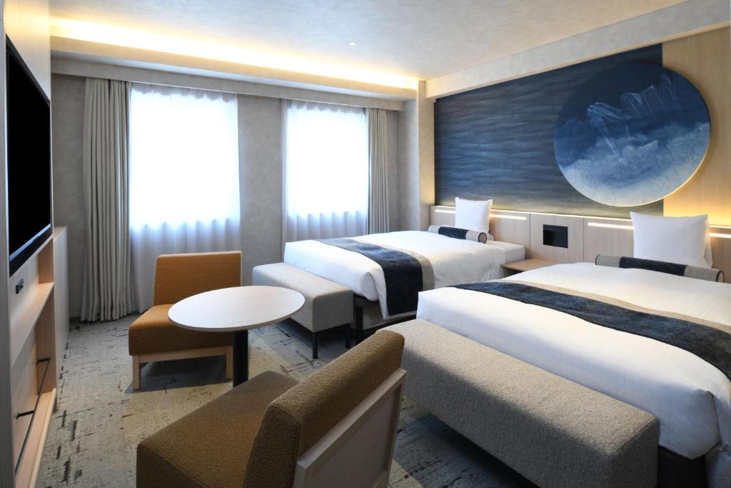 a hotel room with two beds and a tv at HOTEL MYSTAYS Ochanomizu Conference Center in Tokyo
