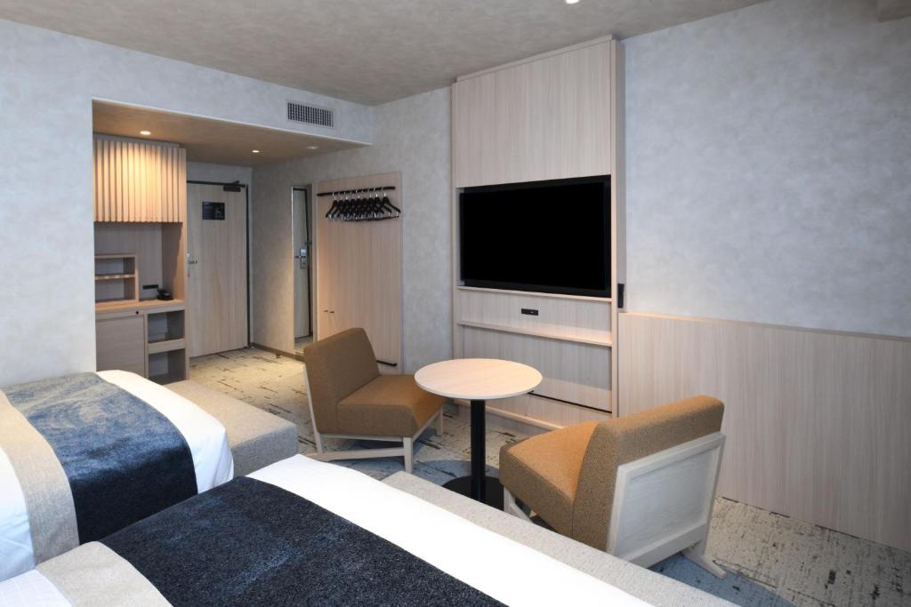 a hotel room with two beds and a flat screen tv at HOTEL MYSTAYS Ochanomizu Conference Center in Tokyo