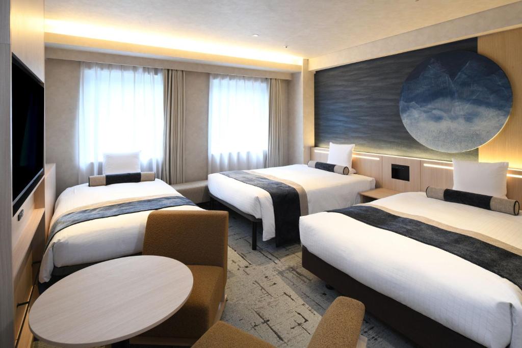 a hotel room with three beds and a table at HOTEL MYSTAYS Ochanomizu Conference Center in Tokyo