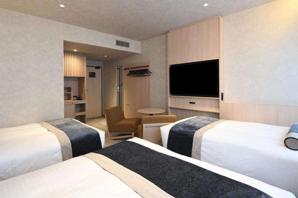 a hotel room with two beds and a flat screen tv at HOTEL MYSTAYS Ochanomizu Conference Center in Tokyo