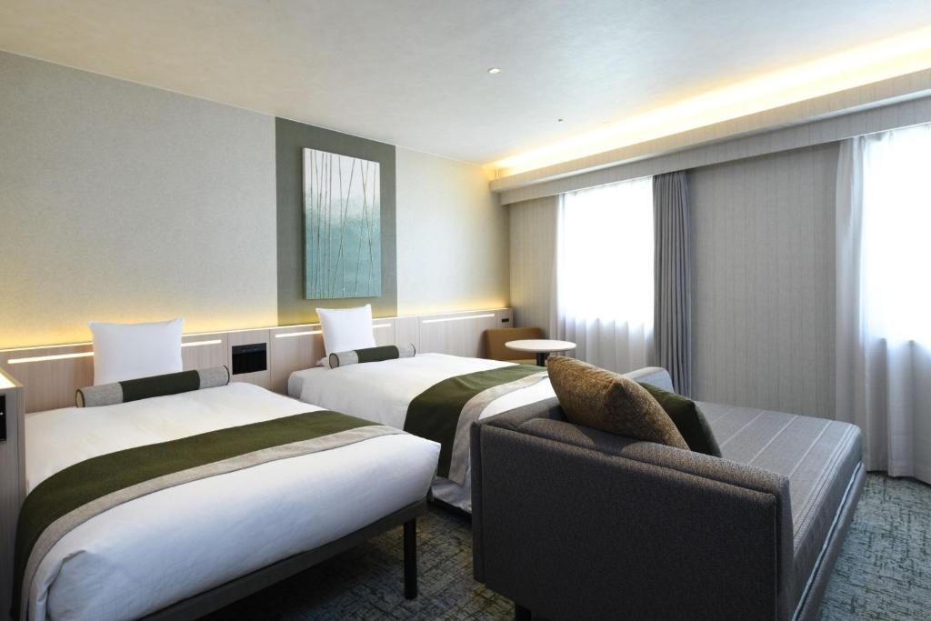 a hotel room with two beds and a couch at HOTEL MYSTAYS Ochanomizu Conference Center in Tokyo