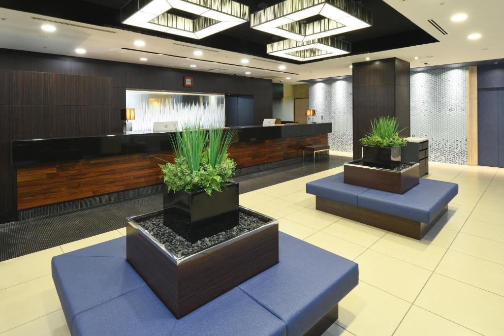 a lobby with three potted plants on blue seats at HOTEL MYSTAYS Ochanomizu Conference Center in Tokyo