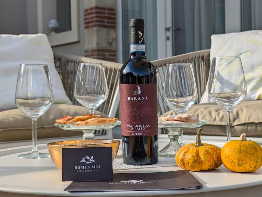 a bottle of wine sitting on a table with pumpkins at Domus MEA - Breakfast Included! in San Martino Buon Albergo