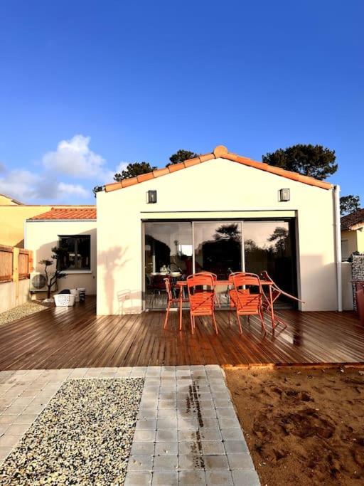 une maison dotée d'une terrasse avec des chaises oranges dans l'établissement L'abri Côtier, à Jard-sur-Mer