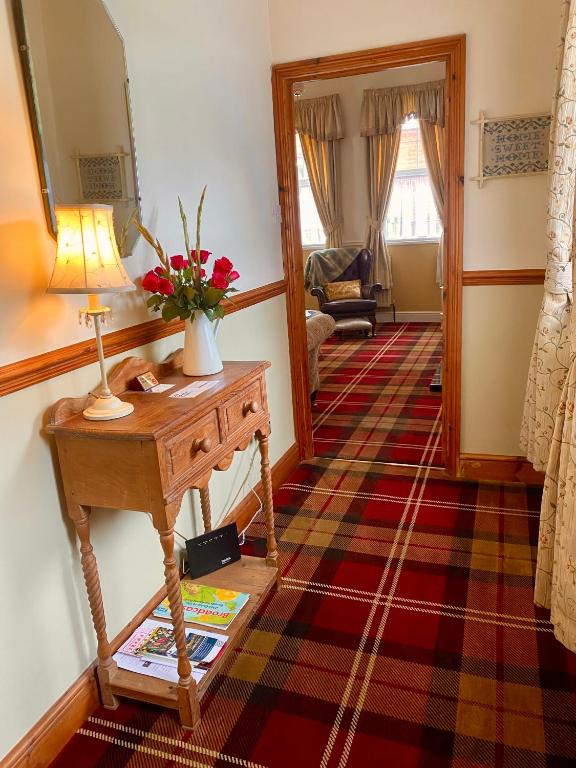 a living room with a table with a lamp and a mirror at Station Cottage in Acle