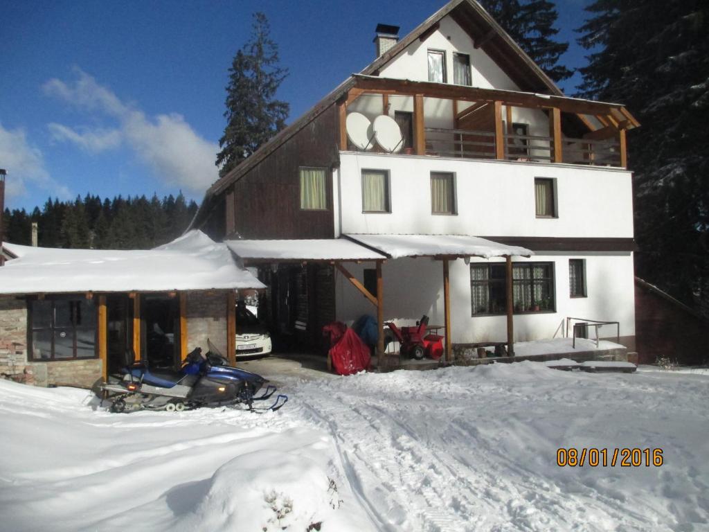 a house in the snow with a snowmobile in front of it at Bed and Breakfast Vila Lala in Jahorina