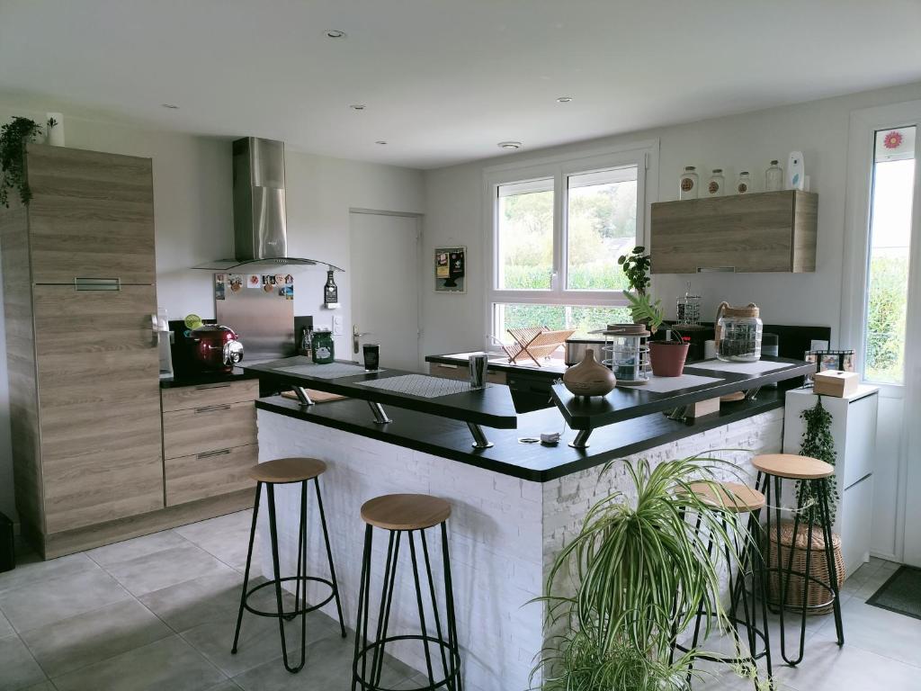 eine Küche mit einer Theke mit Hockern in der Unterkunft Maison au calme in Bournainville